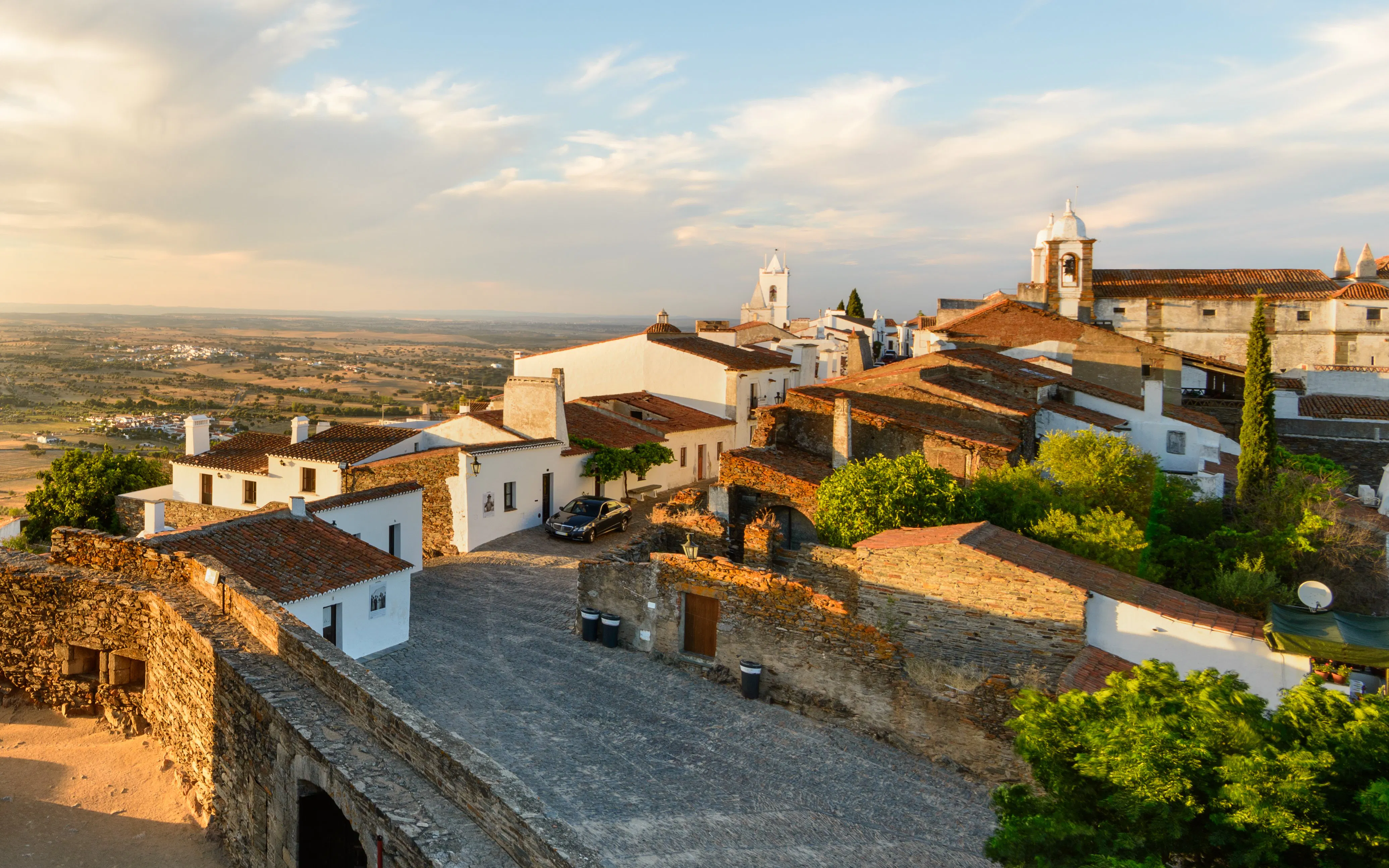 Historic village of Monsaraz, Portugal with whitewashed houses and cobblestone streets at sunset.