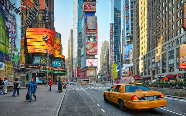 Times Square with yellow taxi and bright billboards, New York City.