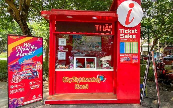 Ticket booth for Saigon Hop-on Hop-Off Sightseeing Tours in Hanoi park setting.
