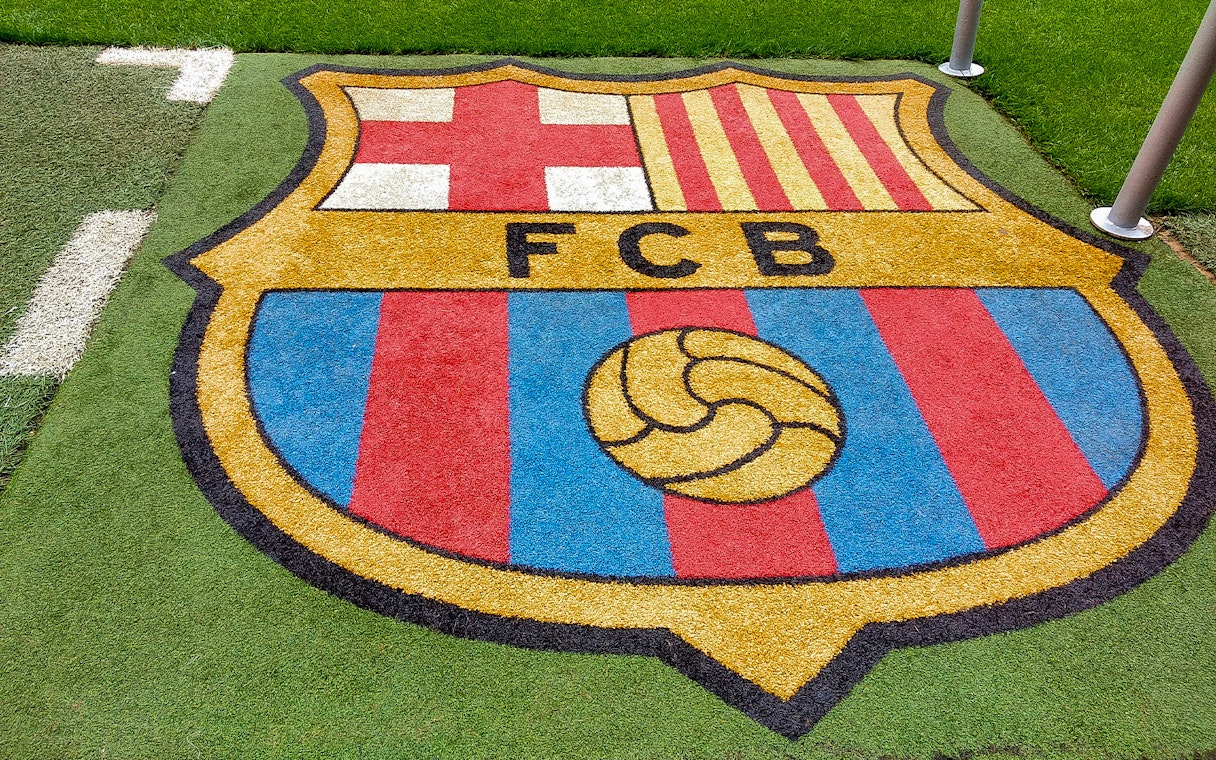 FC Barcelona crest on the grass at Camp Nou stadium.