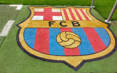 FC Barcelona crest on the grass at Camp Nou stadium.