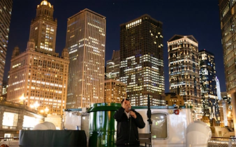 Tour guide narrating on Chicago Haunted River "Creepy Cruise" with city skyline at night.