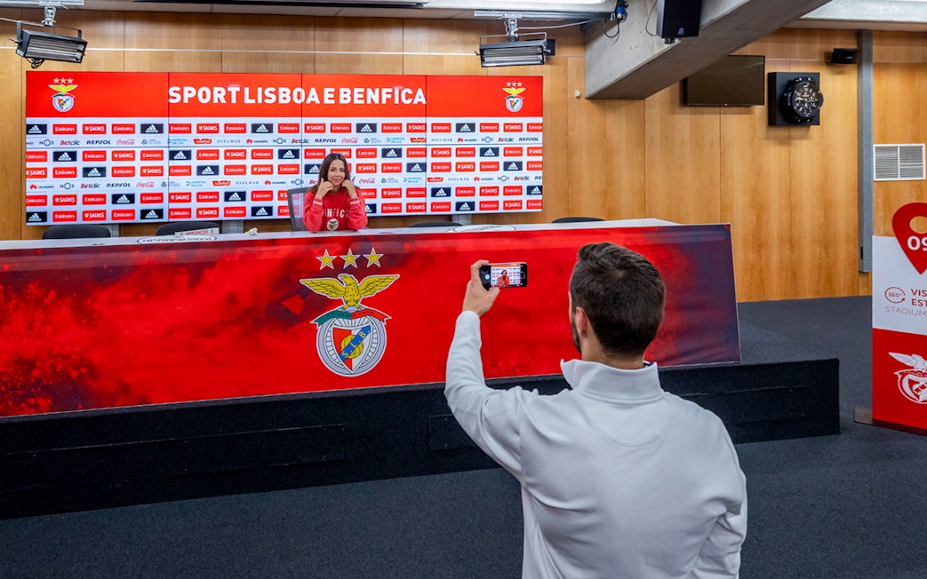 Benfica stadium conference room with a person at the press table and another taking a photo.