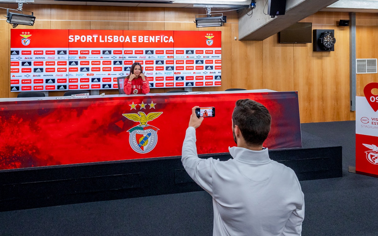 Benfica stadium conference room with a person at the press table and another taking a photo.