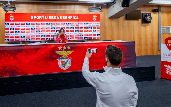 Benfica stadium conference room with a person at the press table and another taking a photo.