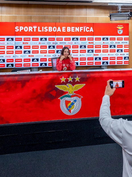 Benfica stadium conference room with a person at the press table and another taking a photo.