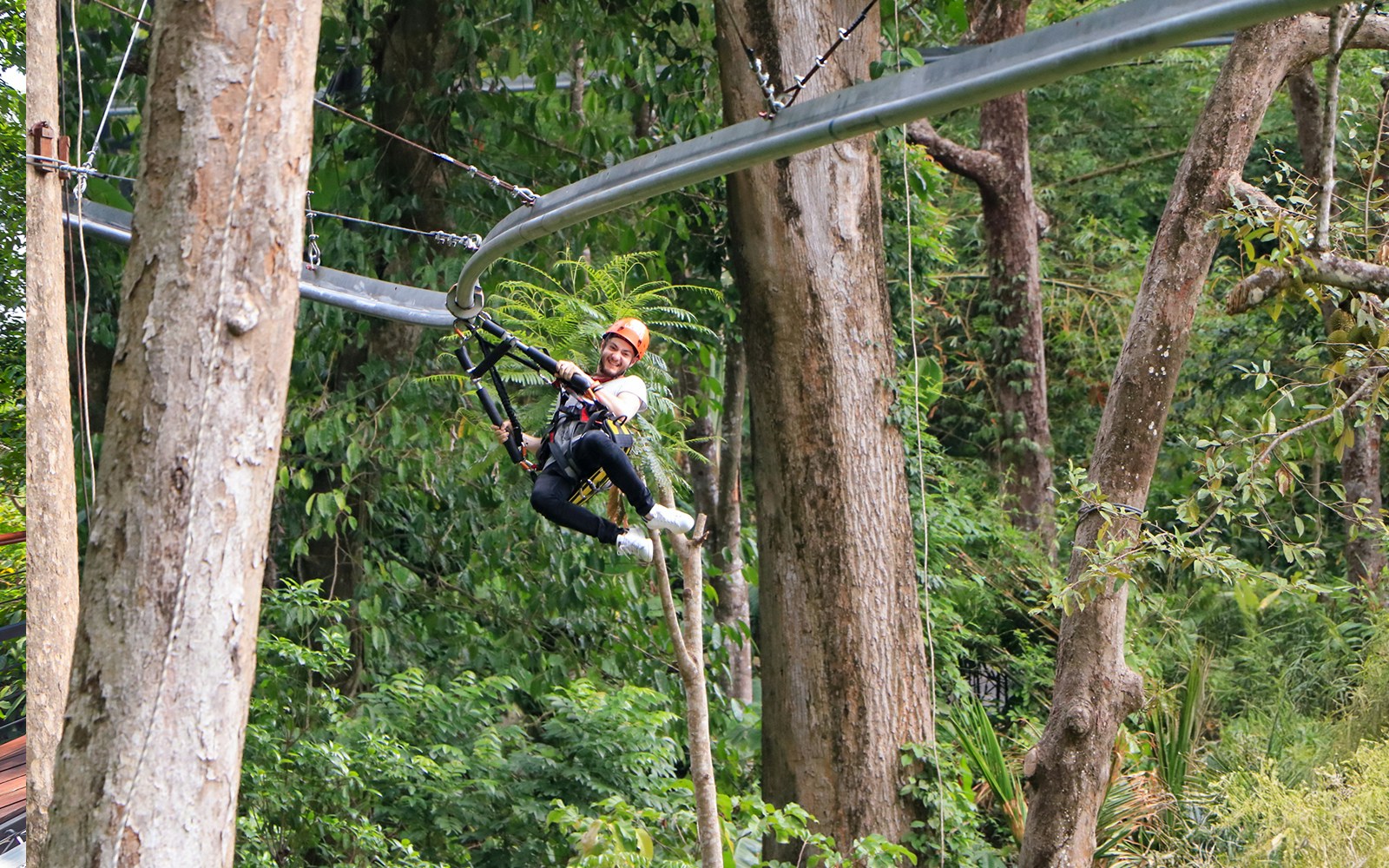 Man ziplining through lush forest at Hanuman World, Phuket.