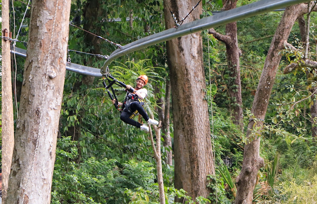 Man ziplining through lush forest in Phuket.