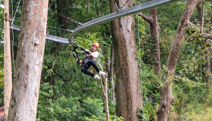 Man ziplining through lush forest at Hanuman World, Phuket.
