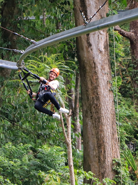 Man ziplining through lush forest in Phuket.