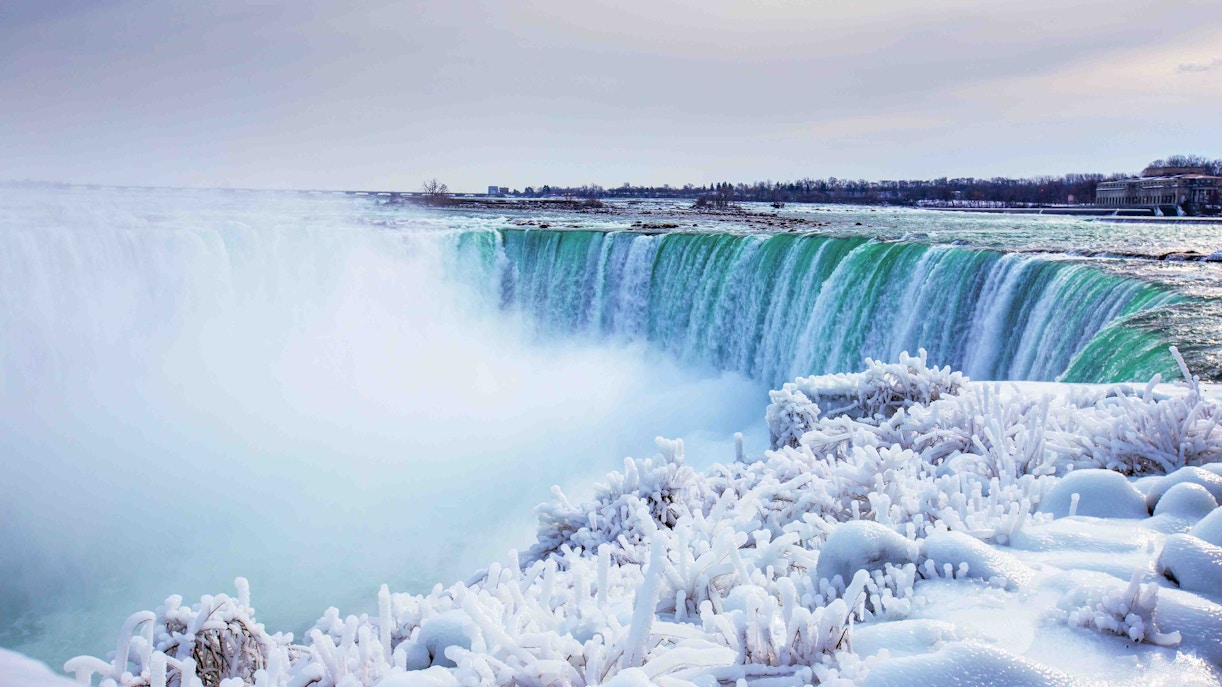 Niagara Falls winter view with snow-covered landscape and flowing waterfalls, Canada.