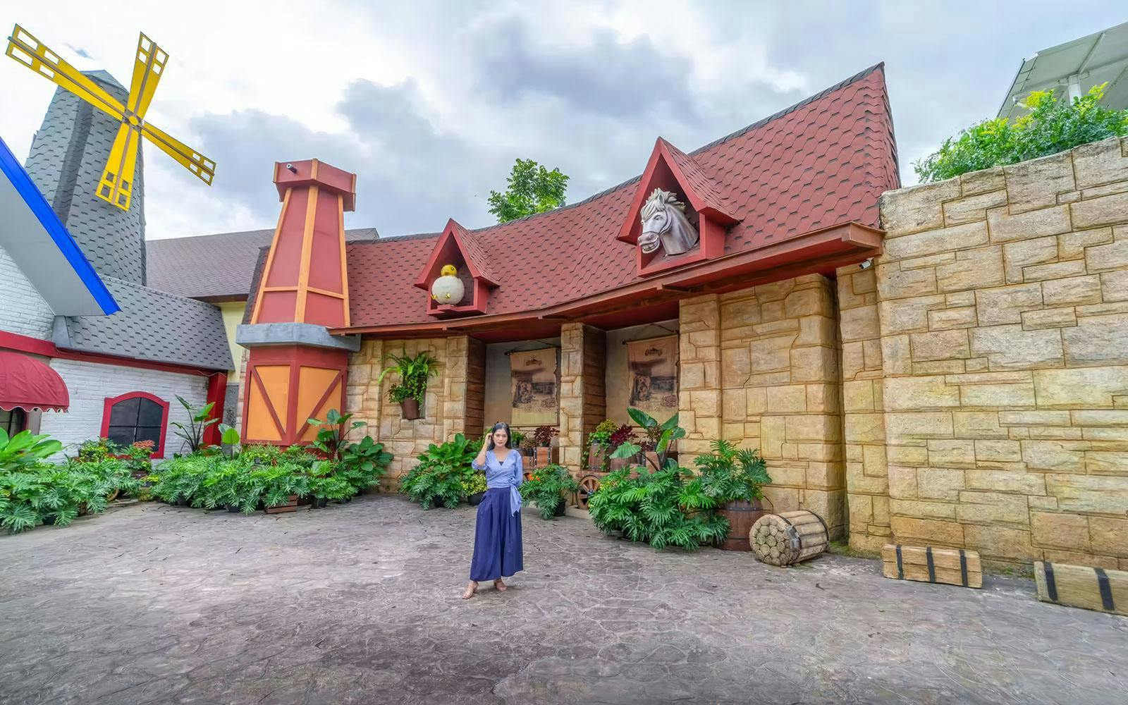 Tourist standing in front of windmill at Dairyland Farm Theme Park.