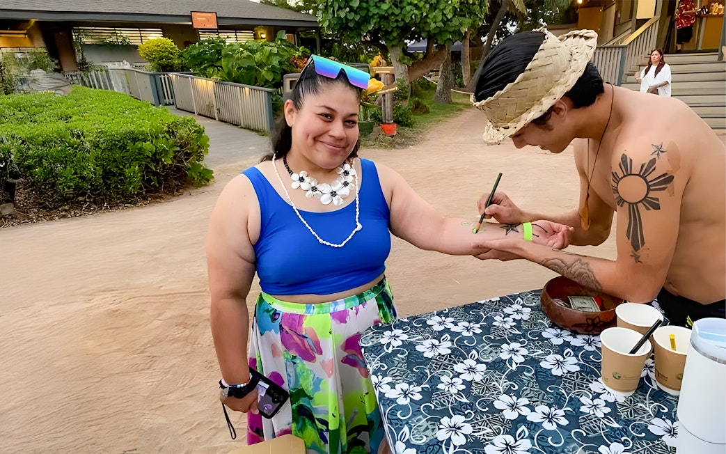 Guest receiving temporary tattoo at Germaine's Luau pre-show cultural activities.