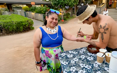 Guest receiving temporary tattoo at Germaine's Luau pre-show cultural activities.
