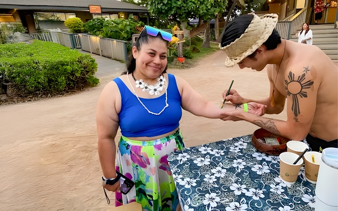Guest receiving temporary tattoo at Germaine's Luau pre-show cultural activities.
