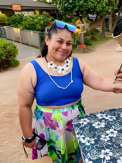 Guest receiving temporary tattoo at Germaine's Luau pre-show cultural activities.