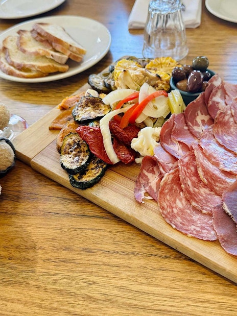 Charcuterie board with meats and vegetables, wine glass, and teddy bear on Yarra Valley tour.
