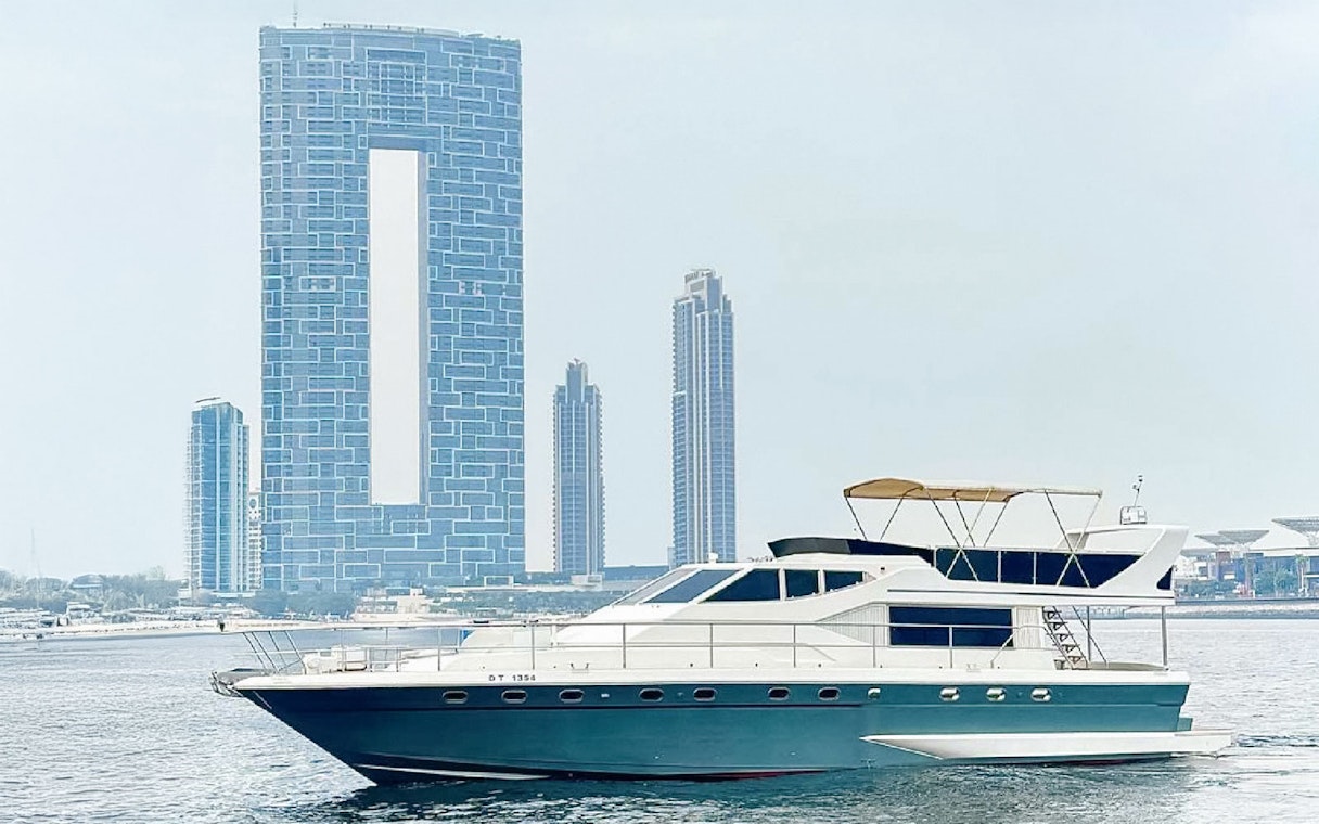 Luxury yacht cruising near Dubai Harbour with city skyline in the background.