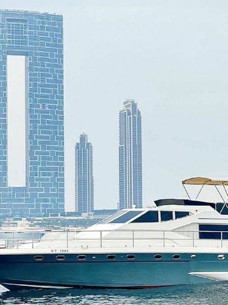 Luxury yacht cruising near Dubai Harbour with city skyline in the background.