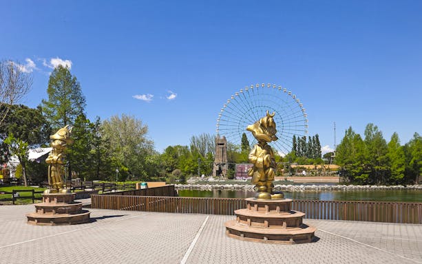 Golden statues and Ferris wheel at Mirabilandia Park, Italy.