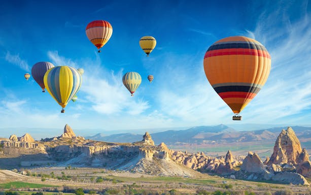 Hot air balloons over Cappadocia landscape during standard tour.