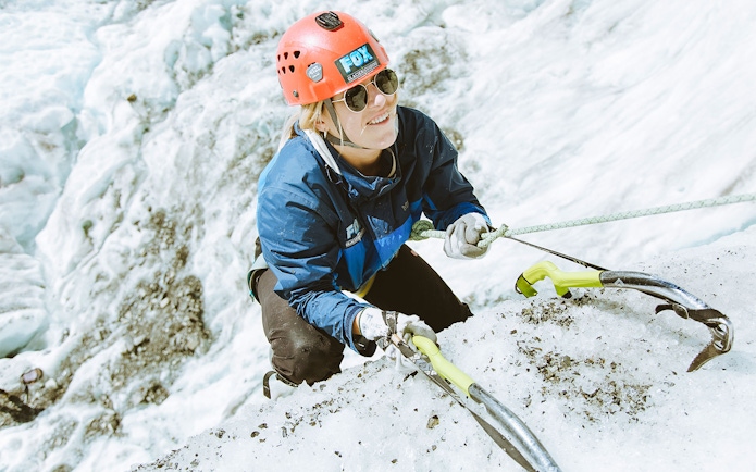 Climber ascending ice wall with gear on Fox Glacier, New Zealand.