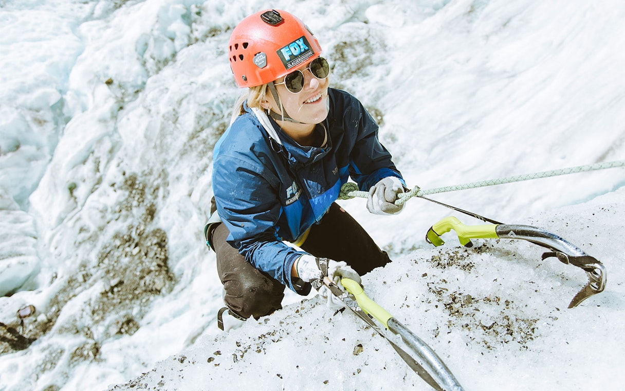Climber ascending ice wall with gear on Fox Glacier, New Zealand.