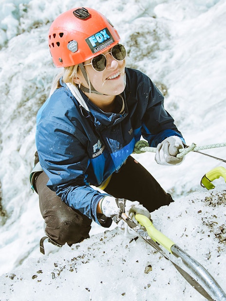Climber ascending ice wall with gear on Fox Glacier, New Zealand.