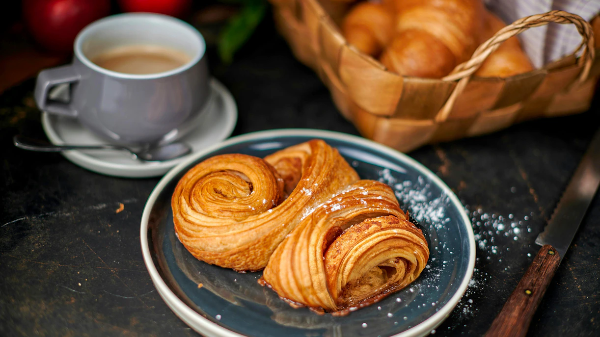 Franzbrötchen pastry on a plate with a cup of latte, Hamburg.
