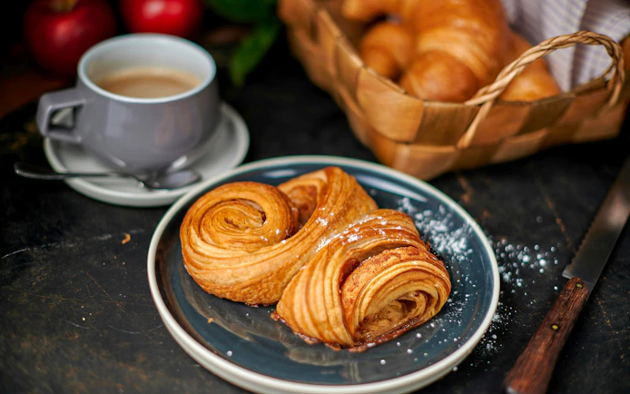 Franzbrötchen pastry on a plate with a cup of latte, Hamburg.