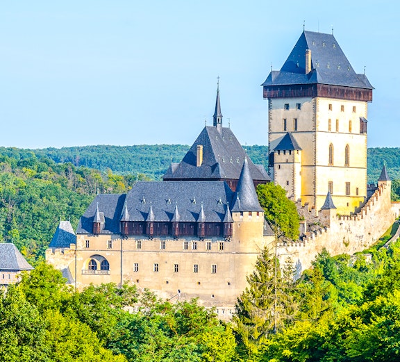 Karlstejn Castle surrounded by lush green forest in the Czech Republic.