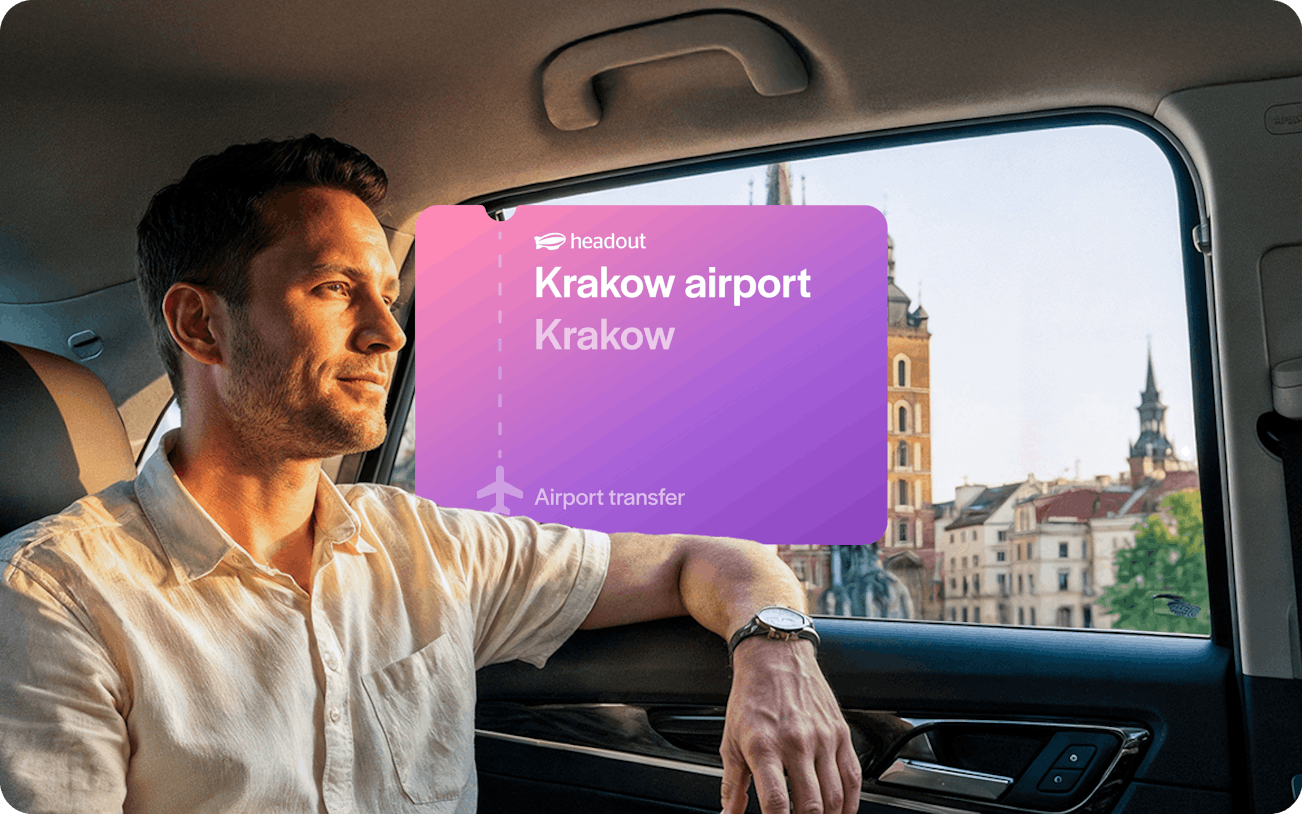 Man in car during Krakow airport transfer with city view in background.