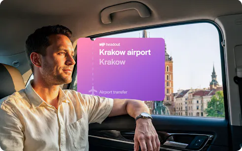Man in car during Krakow airport transfer with city view in background.