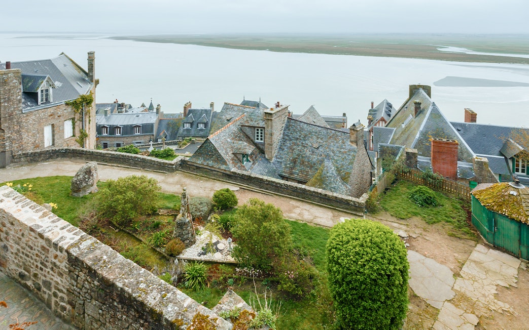 Rampart view of Mont Saint Michel with tourists exploring historic stone buildings.