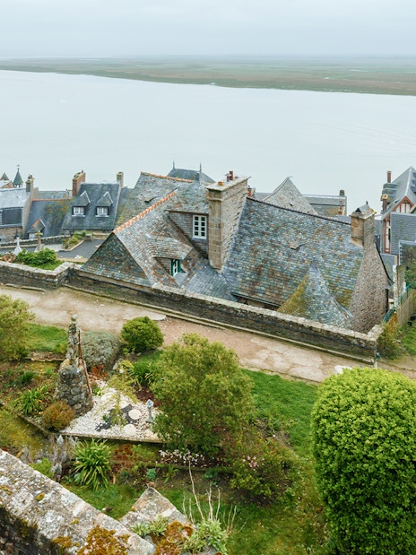 Rampart view of Mont Saint Michel with tourists exploring historic stone buildings.