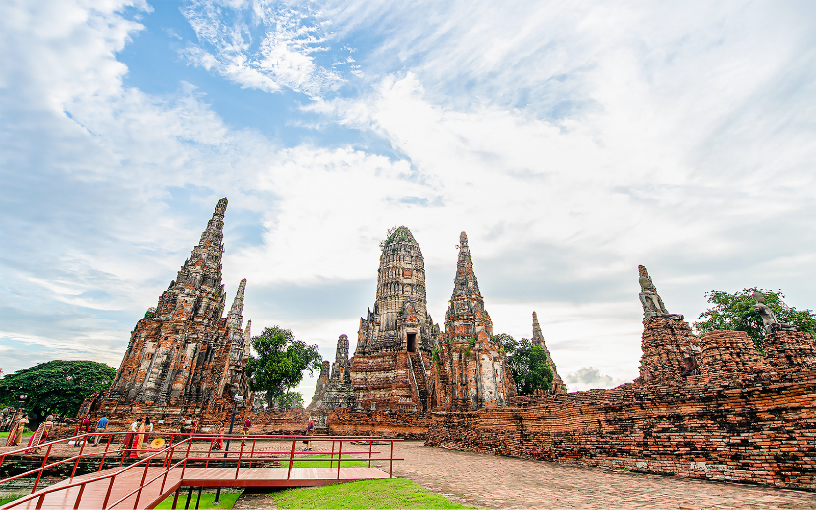 Ayutthaya temple ruins with ancient spires and tourists exploring the site.