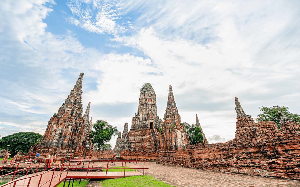 Ayutthaya temple ruins with ancient spires and tourists exploring the site.