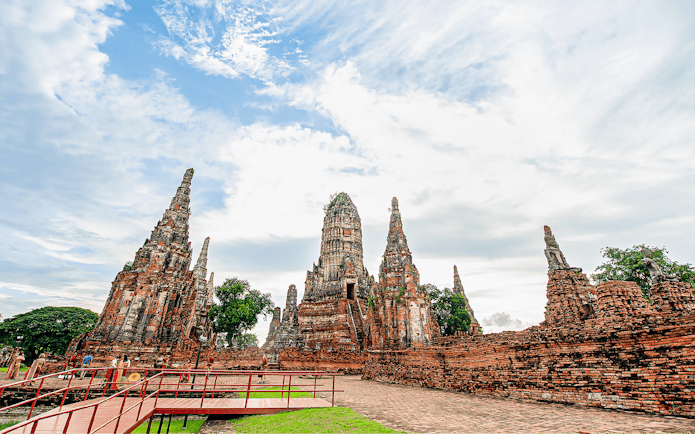 Ayutthaya temple ruins with ancient spires and tourists exploring the site.