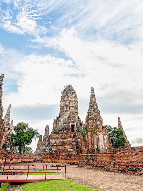 Ayutthaya temple ruins with ancient spires and tourists exploring the site.