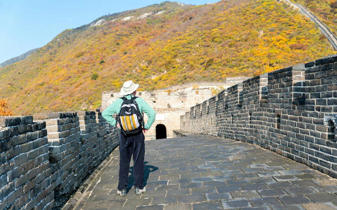 Tourist viewing Mutianyu section of Great Wall, Beijing, during autumn tour.