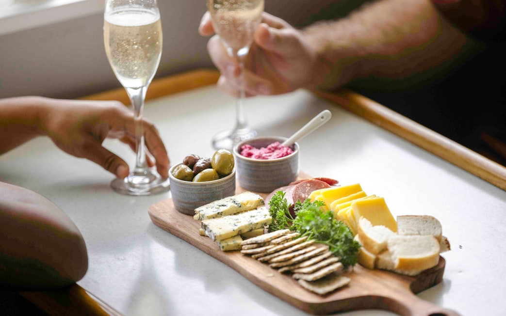 Champagne and charcuterie board with cheeses, meats, and olives on Doubtful Sound cruise.