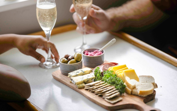 Champagne and charcuterie board with cheeses, meats, and olives on Doubtful Sound cruise.