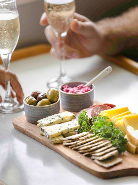 Champagne and charcuterie board with cheeses, meats, and olives on Doubtful Sound cruise.