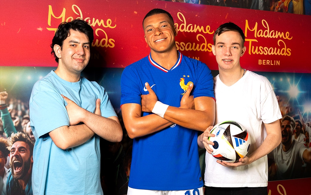 Wax figure of a football player at Madame Tussauds Berlin with two visitors.