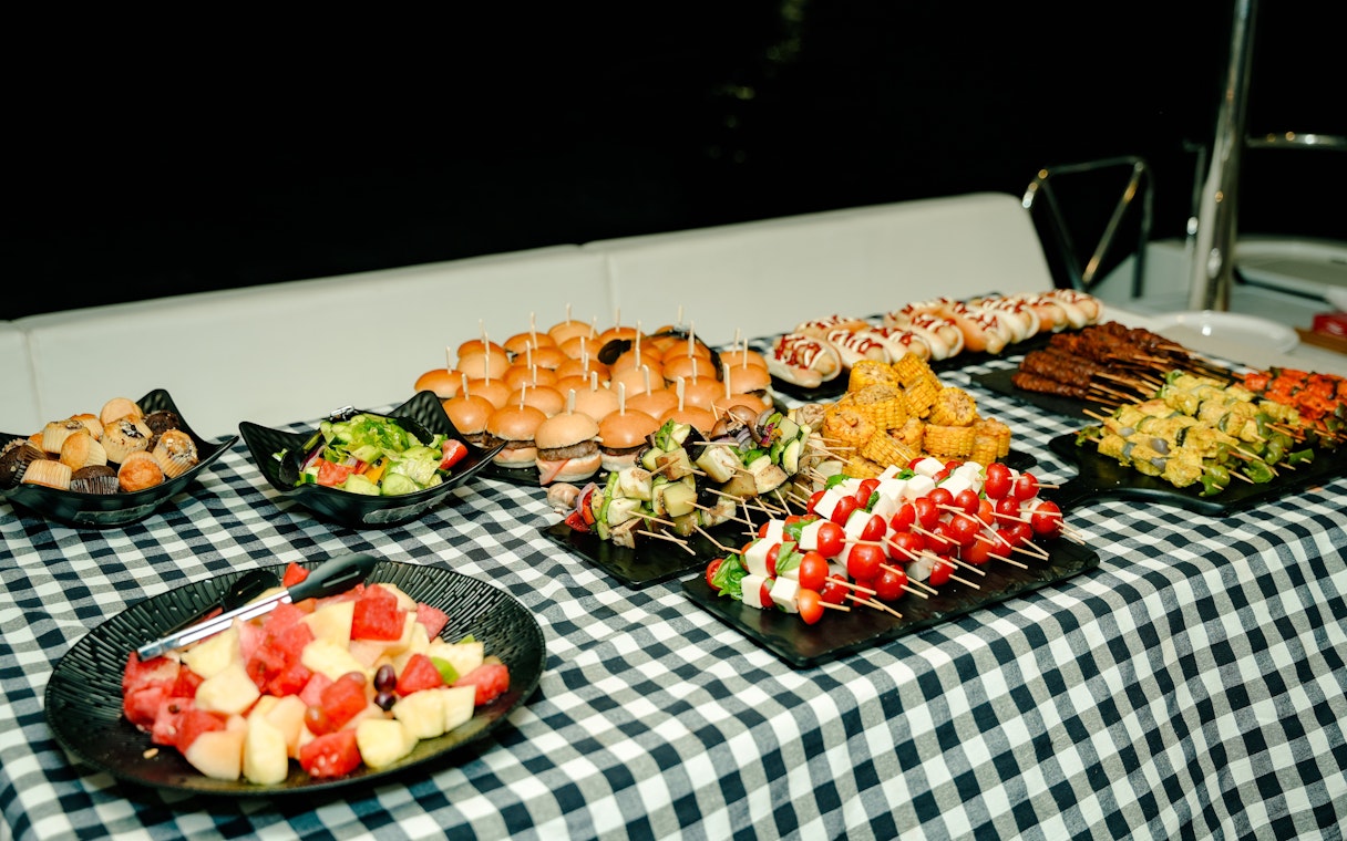 Buffet spread on Dubai Harbour luxury yacht tour with sliders, skewers, and salads.