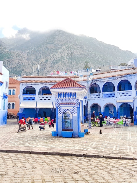Chefchaouen Plaza with blue buildings and central fountain, Morocco.