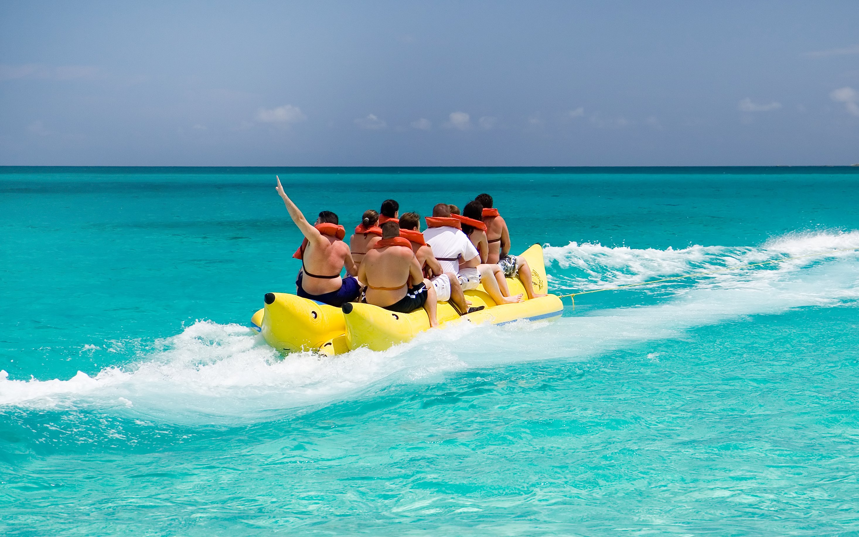 Friends enjoying a banana boat ride on turquoise ocean waters.