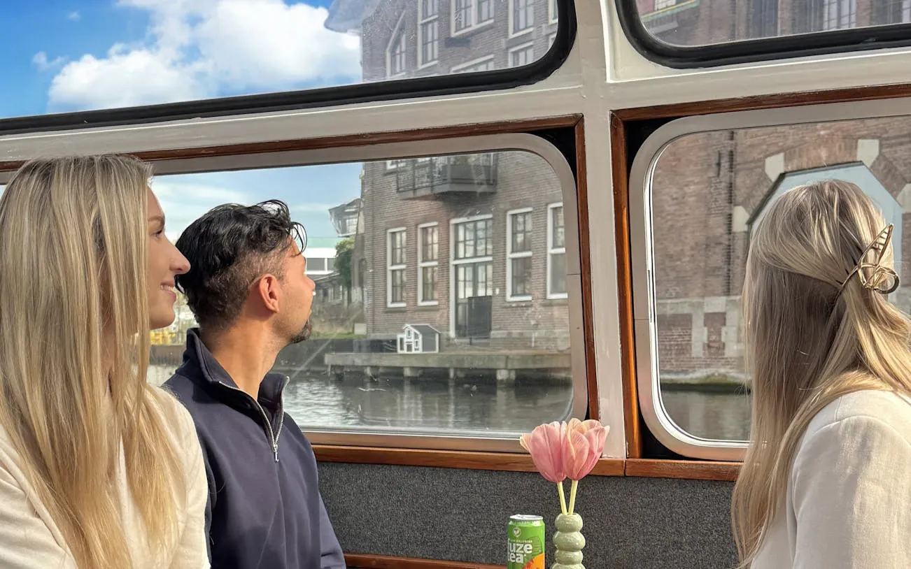 Passengers enjoying Haarlem sightseeing cruise with view of historical buildings.