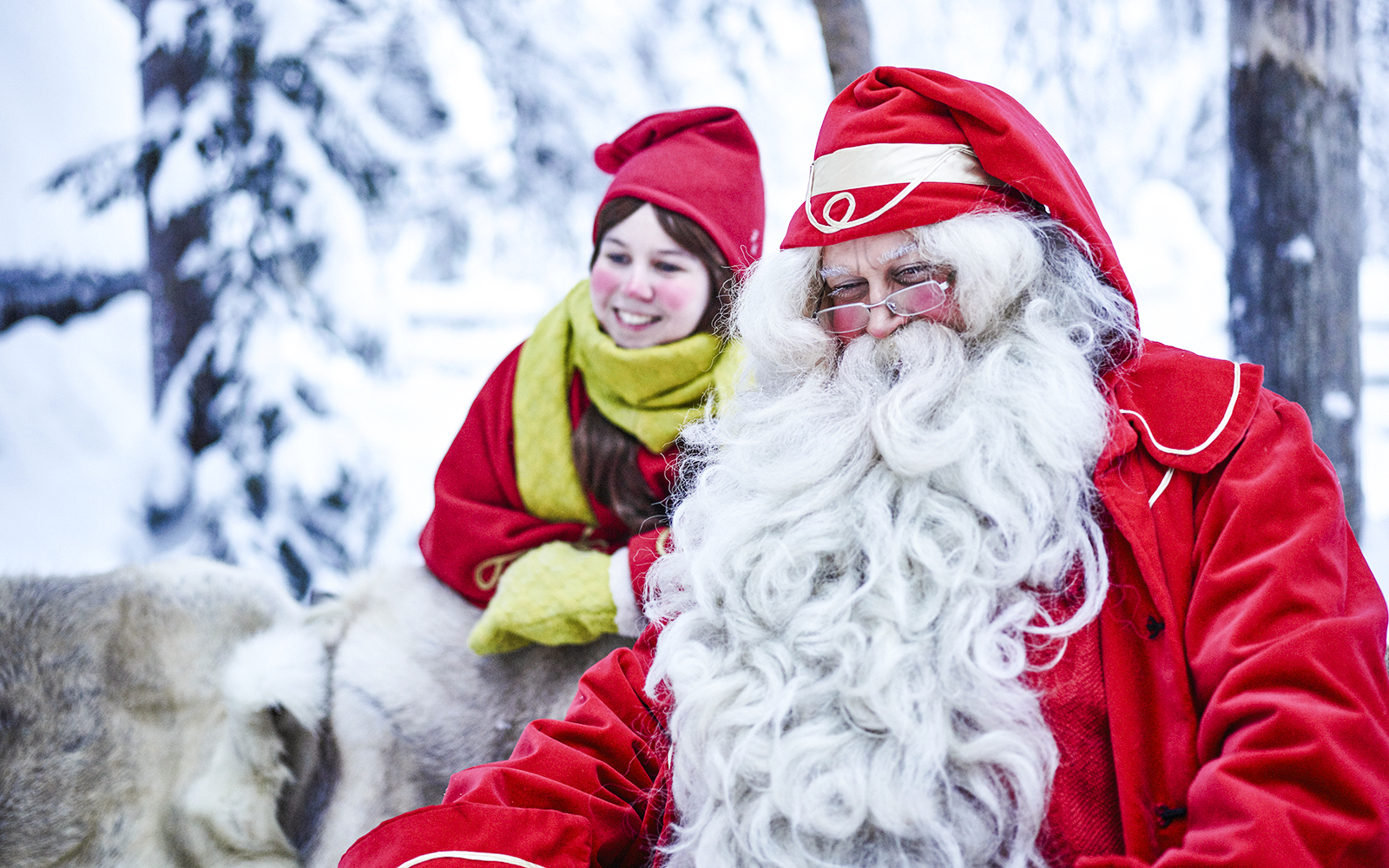 Santa Claus with a child in Santa Claus Village, Lapland, surrounded by snow.