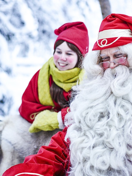 Santa Claus with a child in Santa Claus Village, Lapland, surrounded by snow.